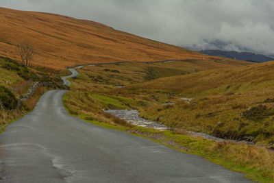 Scenic view of road by mountain against sky