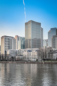 Buildings by river against sky