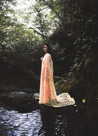 Portrait of woman standing on rock in forest