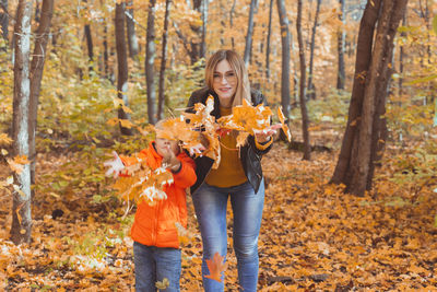 Portrait of mother and son holding leaves in forest