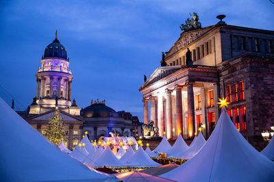 Gendarmenmarkt christmas market during blue hour, historic buildings illuminated at night. 