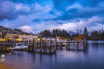 Sailboats moored at harbor against sky at dusk