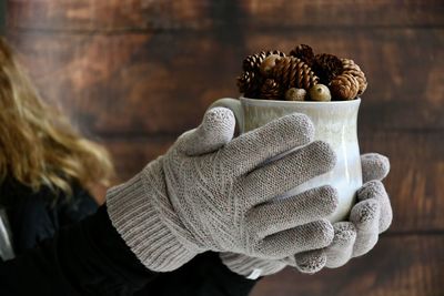 Midsection of woman holding coffee cup with pine cone at home