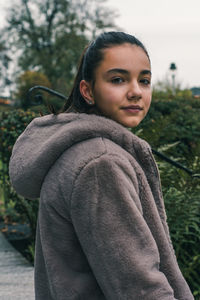 Portrait of young woman standing against trees