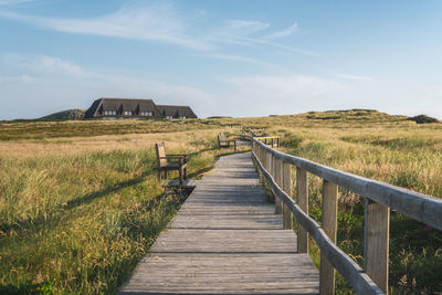 Boardwalk on field against sky