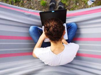 Directly above shot of woman using laptop while relaxing on hammock