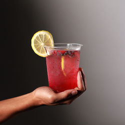 Cropped hand holding drink against white background