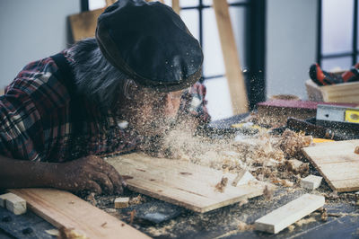 Carpenter with planks on table in workshop