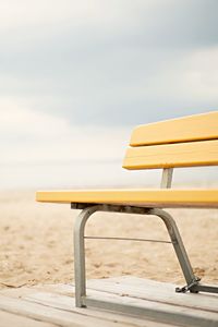 Close-up of cropped bench on shore against the sky