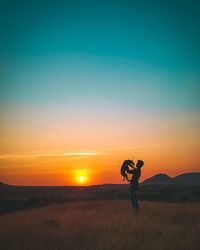 Man standing on field against sky during sunset