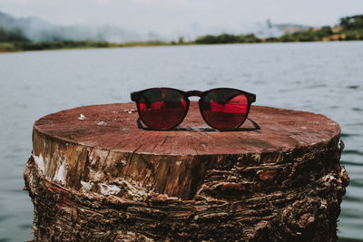 Close-up of sunglasses on tree stump by lake