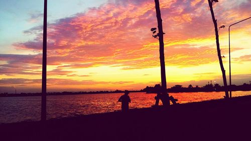 Silhouette man on beach against orange sky