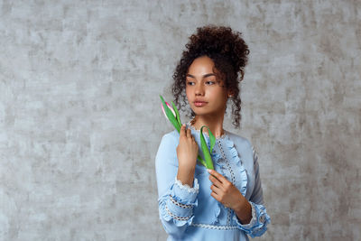 Portrait of woman standing against wall