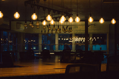 Illuminated pendant lights in restaurant at night