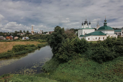 Houses by river and buildings against sky