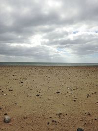 Scenic view of beach against cloudy sky