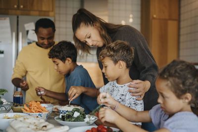 Parents teaching children to cook food in kitchen at home