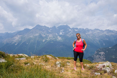 Scenic view of woman standing in front of mountain. woman standing on mountain against sky