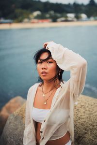 Portrait of young woman standing at beach