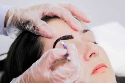 Cropped hand of beautician using cotton swab on female customer