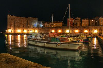 Boats in river with illuminated buildings in background