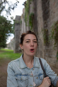 Portrait of woman with mouth open standing against built structure