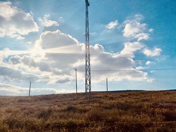 Low angle view of electricity pylon on field against sky