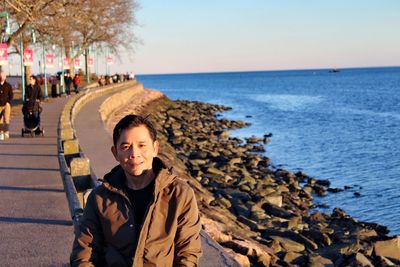 Portrait of woman sitting on beach against sky