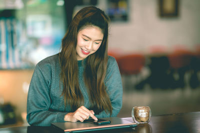 Young woman using mobile phone at restaurant