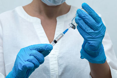 Midsection of doctor holding syringe with vial at hospital