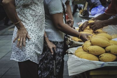 Midsection of people holding food at market stall
