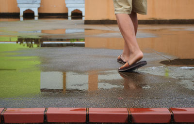 Low section of woman standing on wet floor during rainy season
