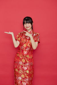 Portrait of young woman against red background