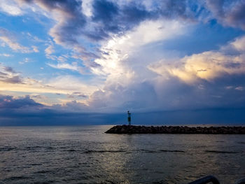 Lighthouse amidst sea and buildings against sky