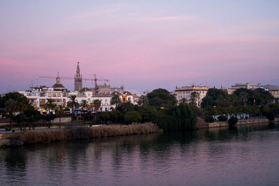 River in city against sky during sunset