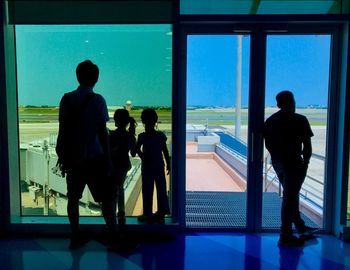 Rear view of silhouette people looking through window