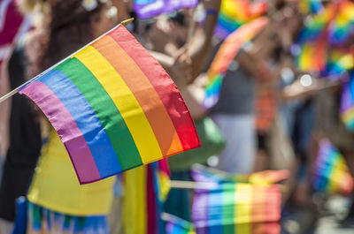 Close-up of rainbow flag with crowd in background during parade