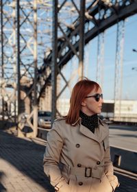 Young woman standing on bridge during sunny day