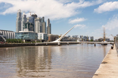 Bridge over river against sky in city