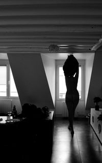 Rear view of silhouette woman undressing at home