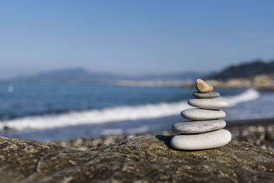 Stack of stones at beach against sky