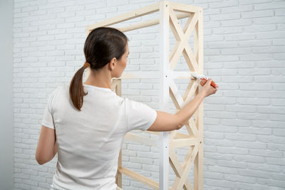 Rear view of woman standing against wall