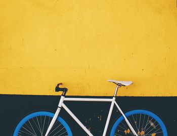 Blue bicycle against yellow wall