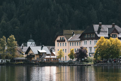 Houses by lake and buildings against sky