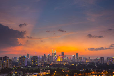 Illuminated cityscape against sky during sunset