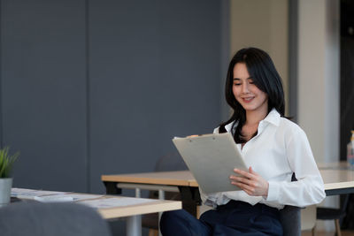 Portrait of a smiling young woman reading book