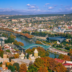 High angle view of illuminated city by river against sky