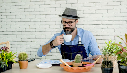 Portrait of man holding ice cream sitting on table