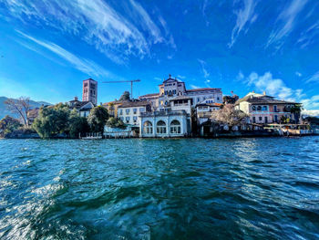 View of buildings by sea against blue sky