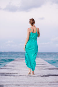 Rear view of woman walking on pier against sea